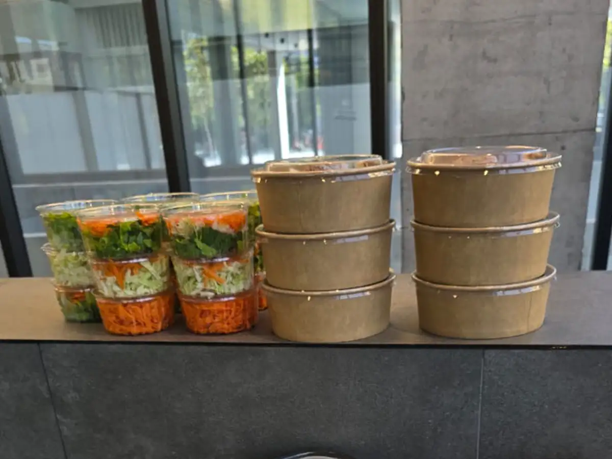 Pedido corporativo con envases sellados y ensaladas individuales listo para entregar en el lobby de una oficina en Providencia